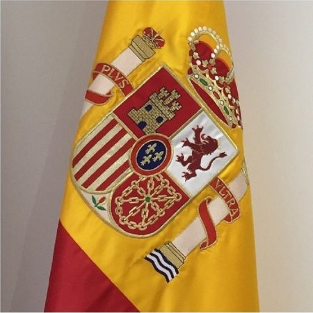 IMAGEN DE UN ESCUDO BORDADO SOBRE UNA BANDERA DE ESPAÑA